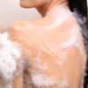 背中ニキビに悩む女性が背中ニキビを治すために、抗真菌成分であるミコナゾール硝酸塩配合のコラージュフルフル 泡石鹸で身体を洗っているイメージ写真。